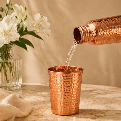 Wasser wird aus Kupferflasche in den Kupferbecher gegossen